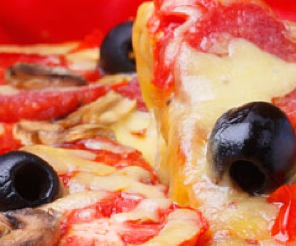 Baked hot pizza with one slice on lifter with fire on background